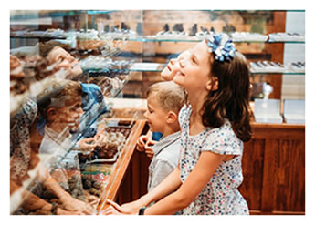 Young children smiling looking at Marie's Candies Showcase